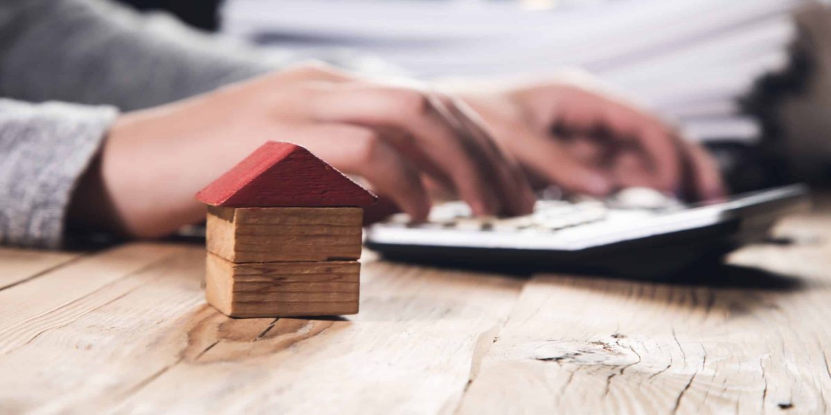 Hand a real estate agent sign with home model.