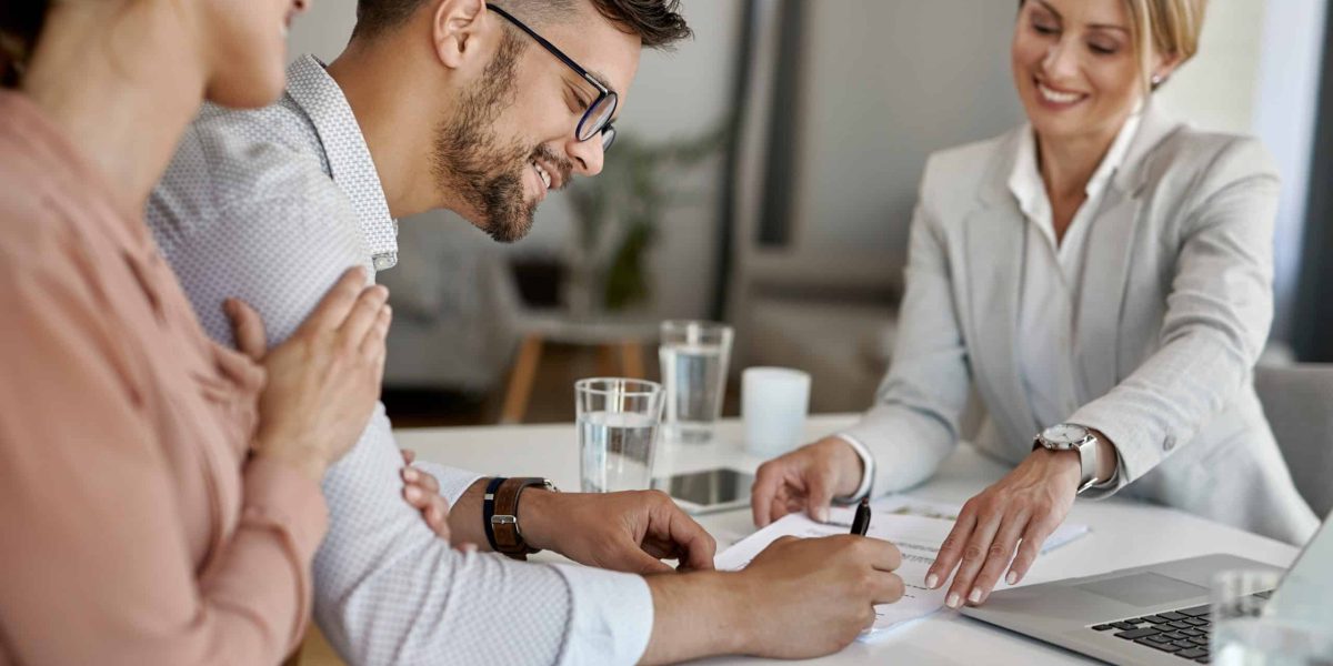 Happy man and his wife having a meeting with financial advisor and signing an agreement in the office.