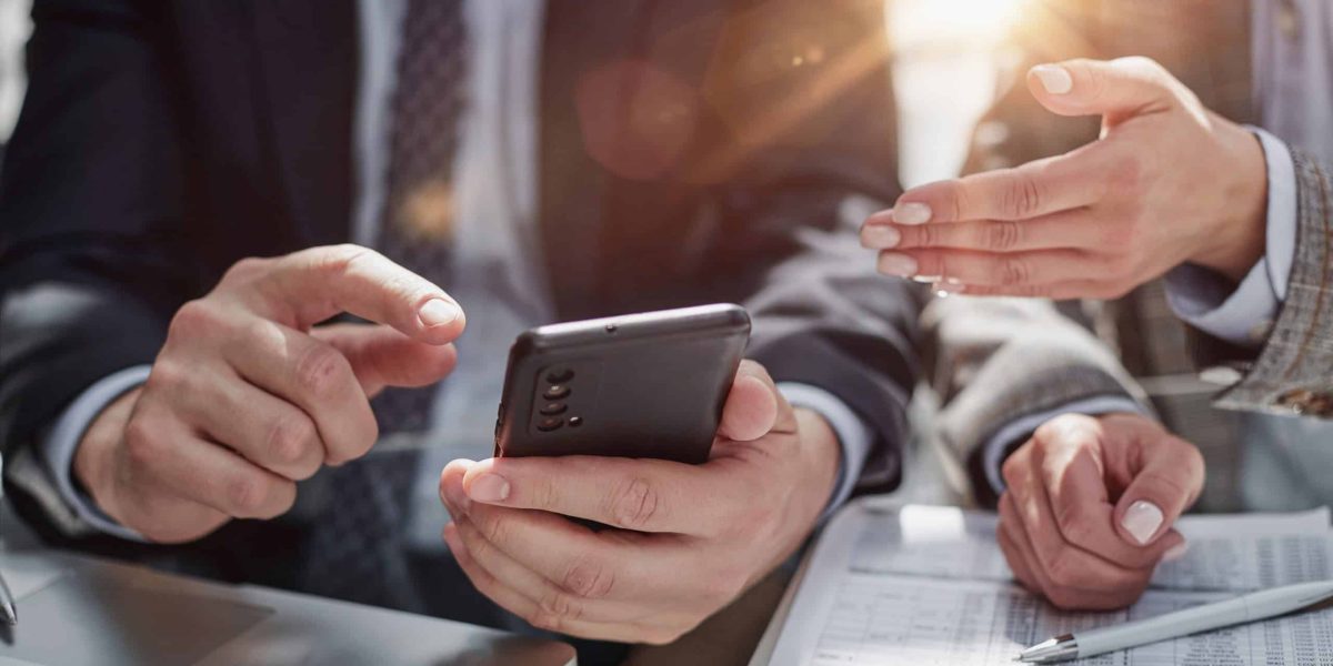 manager uses smartphone while sitting at table with colleague in office