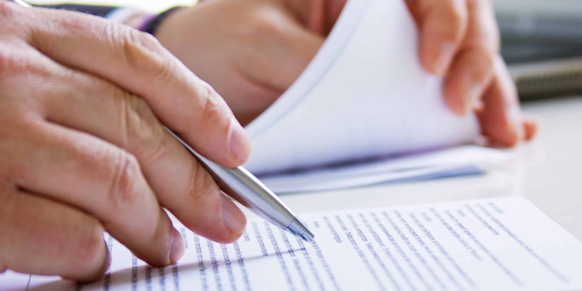 Hands of Business man in dark suit writing in his datebook