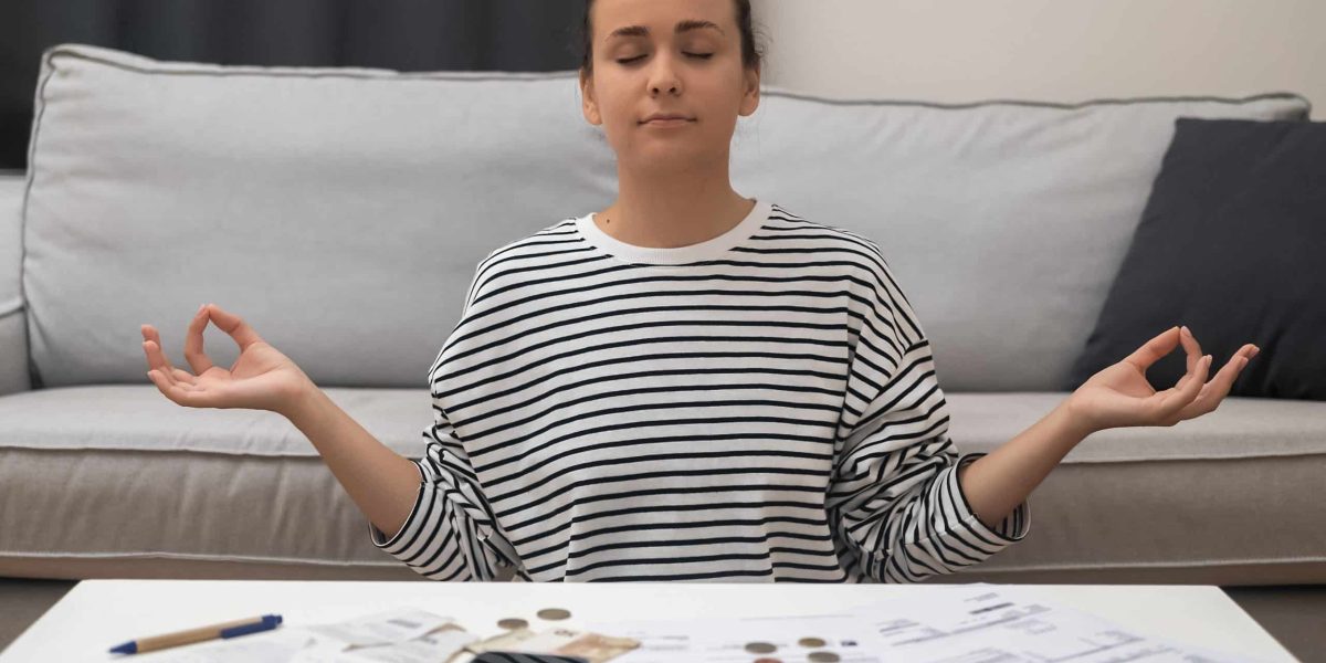Zen Financial Recovery: A woman meditates in a lotus position, finding inner calm after financial stress from calculating utility bills and taxes.