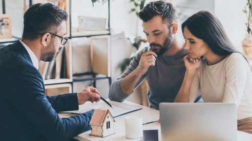 Asesor hipotecario revisando la situación financiera de una pareja para evaluar sus posibilidades de conseguir una hipoteca en España