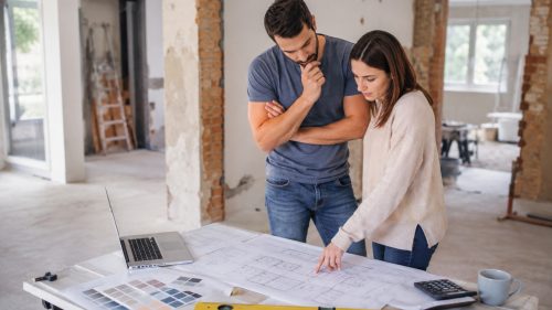 Pareja revisando los planos y el presupuesto de una reforma integral en una vivienda mientras estudia opciones de financiación hipotecaria