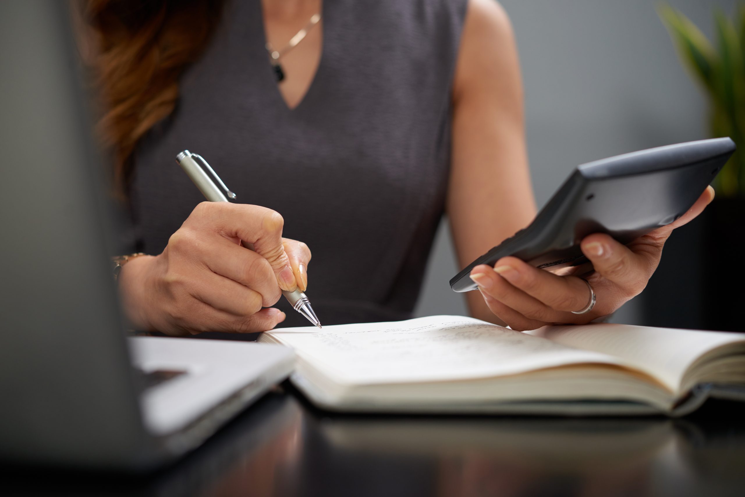 Close-up image of business lady making calculations and taking notes